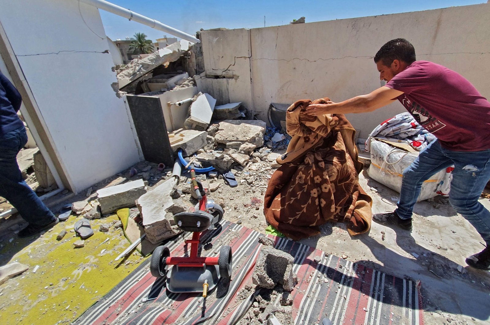 Residents salvage some belongings amidst the rubble of a building that was damaged when forces loyal to putschist Gen. Khalifa Haftar shelled the residential neighborhood of Znatah in the Libyan capital Tripoli,  May 1, 2020. (AFP)