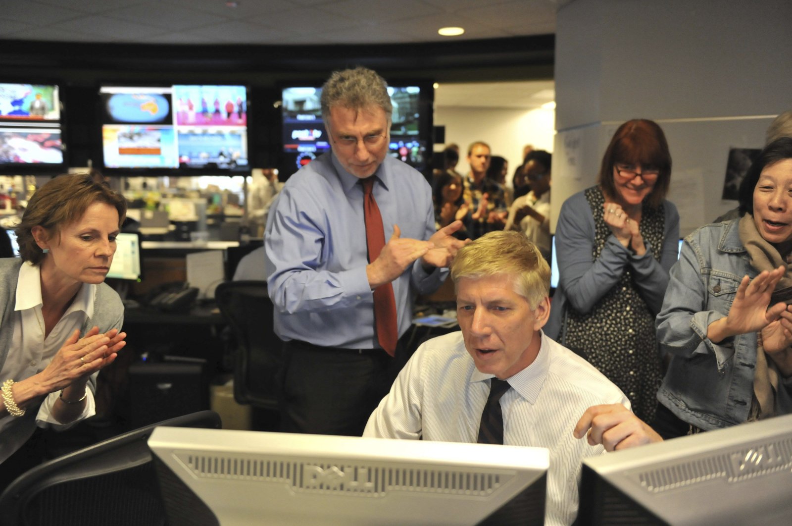 Editors huddle around a computer as they read the list of 2014 Pulitzer Prize winners, April 14, 2014. (Marlon Correa/The Washington Post via Reuters Photo)