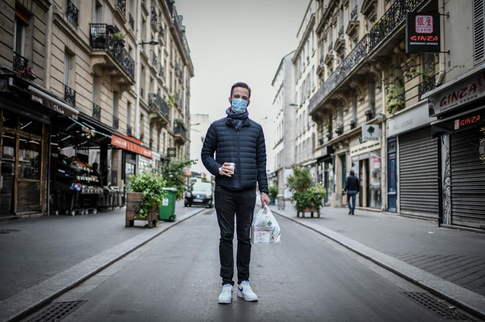 A man, wearing a protective face mask, poses for a photograph in the streets of Paris on May 4, 2020, (AFP Photo)