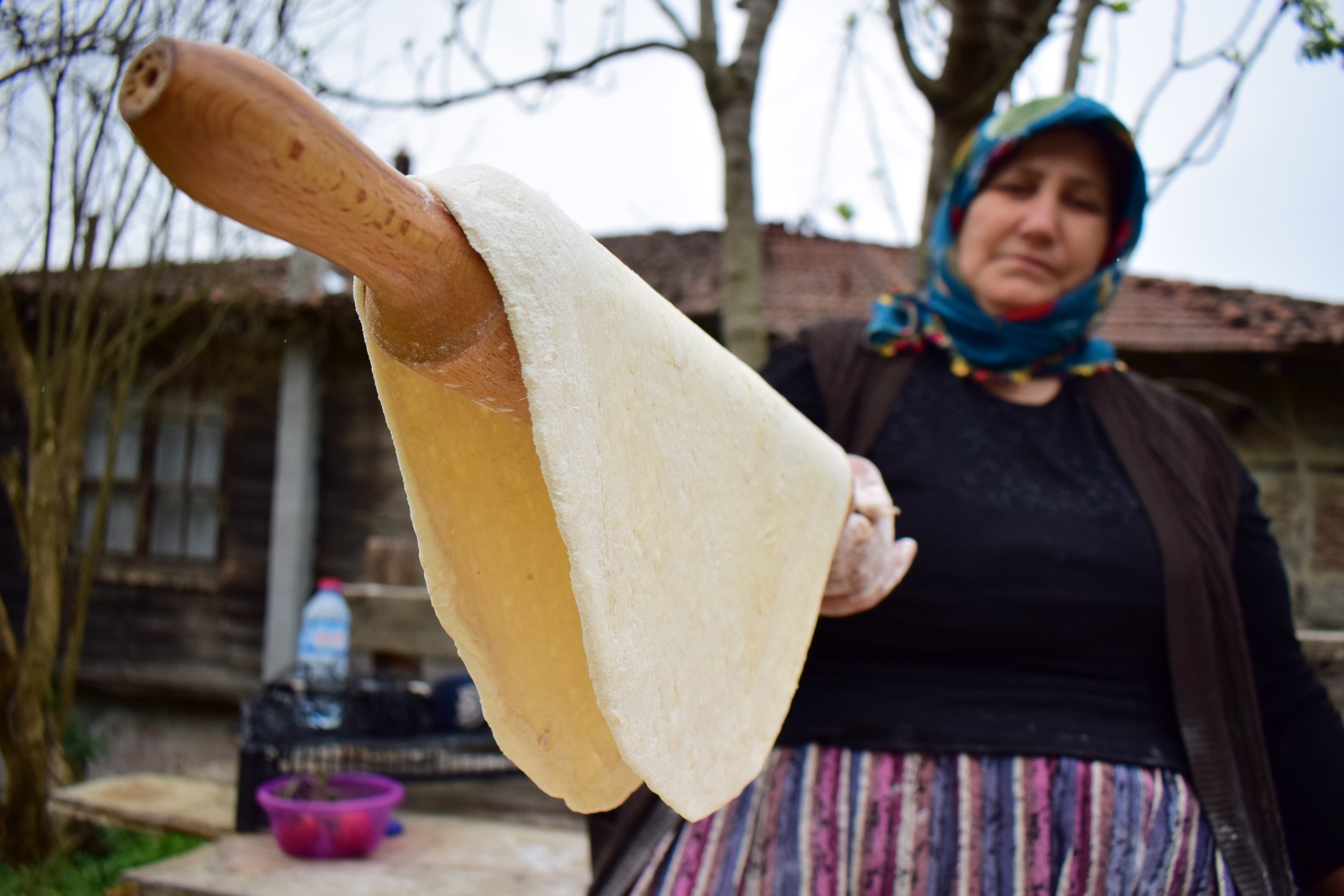 A woman holds up dough on a rolling pin as she prepares pide, in Çayağzı village, Düzce province, Turkey, April 26, 2020. (AA Photo)