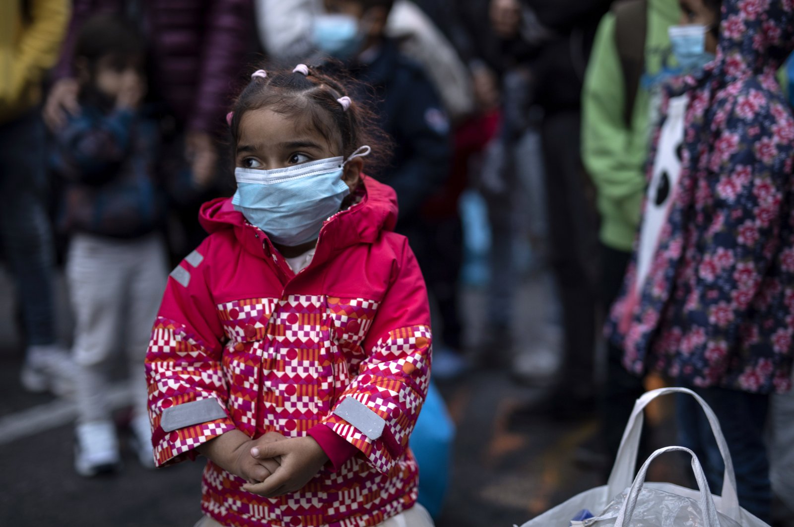 A young girl wearing a mask to prevent the spread of the coronavirus, looks on after refugees and migrants arrived at the port of Piraeus, near Athens, on Monday, May 4, 2020. (AP Photo)