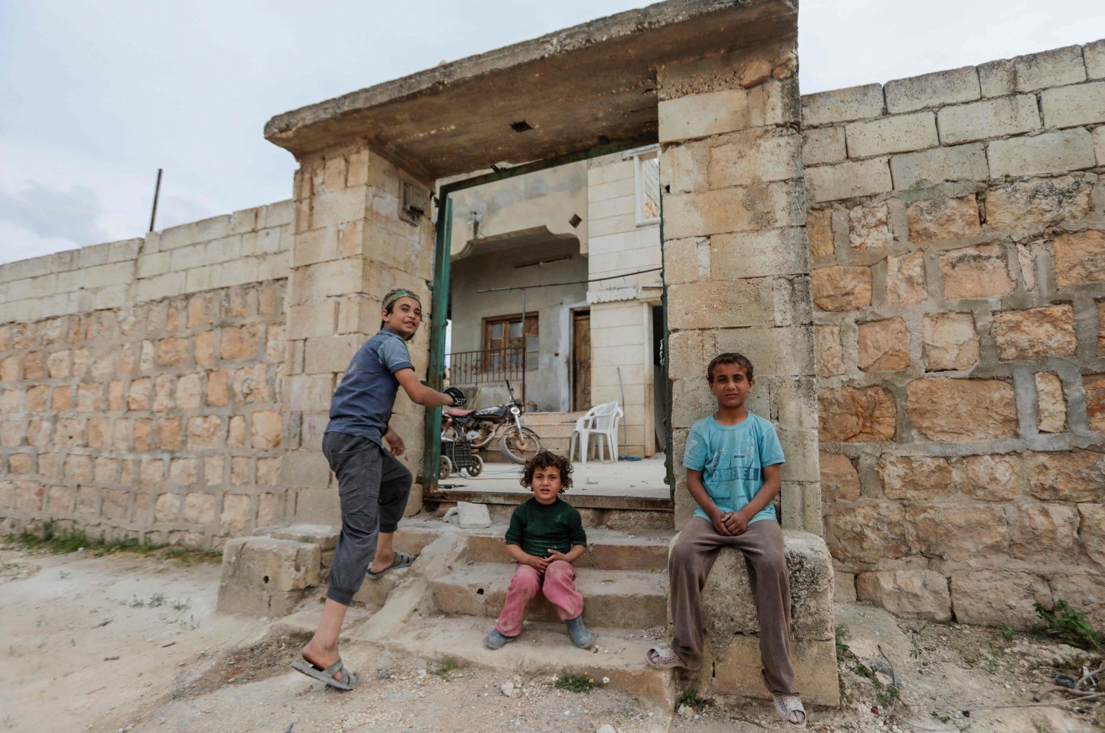 Syrian children whose family decided to return home, rest by the entrance as they clean the rubble from their house's yard in al-Nayrab, a village ravaged by regime forces bombardment near the M4 strategic highway, in Syria's northwestern Idlib province, May 3, 2020. (AFP Photo)