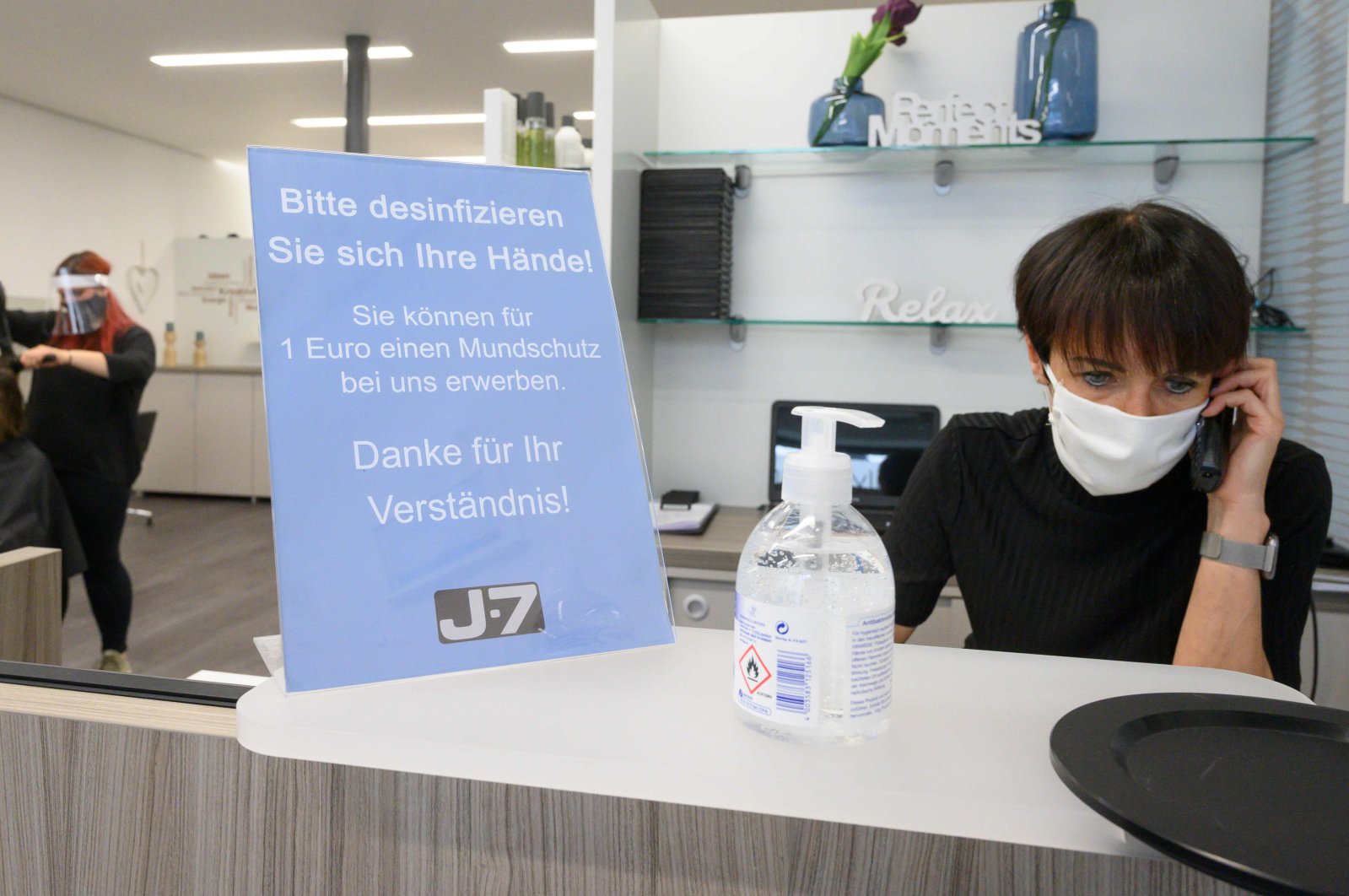 A hairdresser wears a face mask as she talks on the phone in her hairdressing salon, Ludwigsburg, May 4, 2020. (AFP Photo)