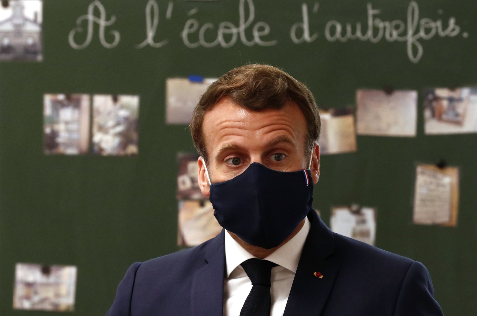 French President Emmanuel Macron, wearing a protective face mask, speaks with schoolchildren during a class at the Pierre Ronsard elementary school in Poissy, outside Paris, May 5, 2020. (AP Photo)