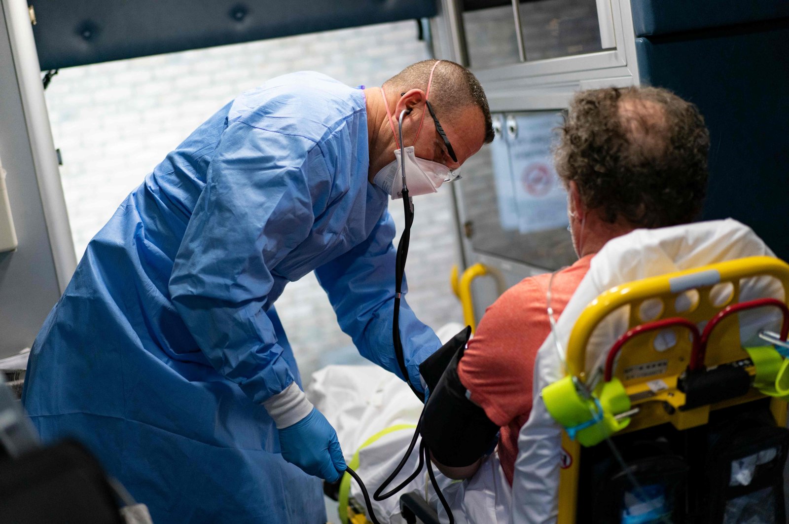 A firefighter with Anne Arundel County Fire Department takes the blood pressure of a suspected COVID-19 patient as he is transported to the hospital in Glen Burnie, Maryland, May 3, 2020. (AFP Photo)