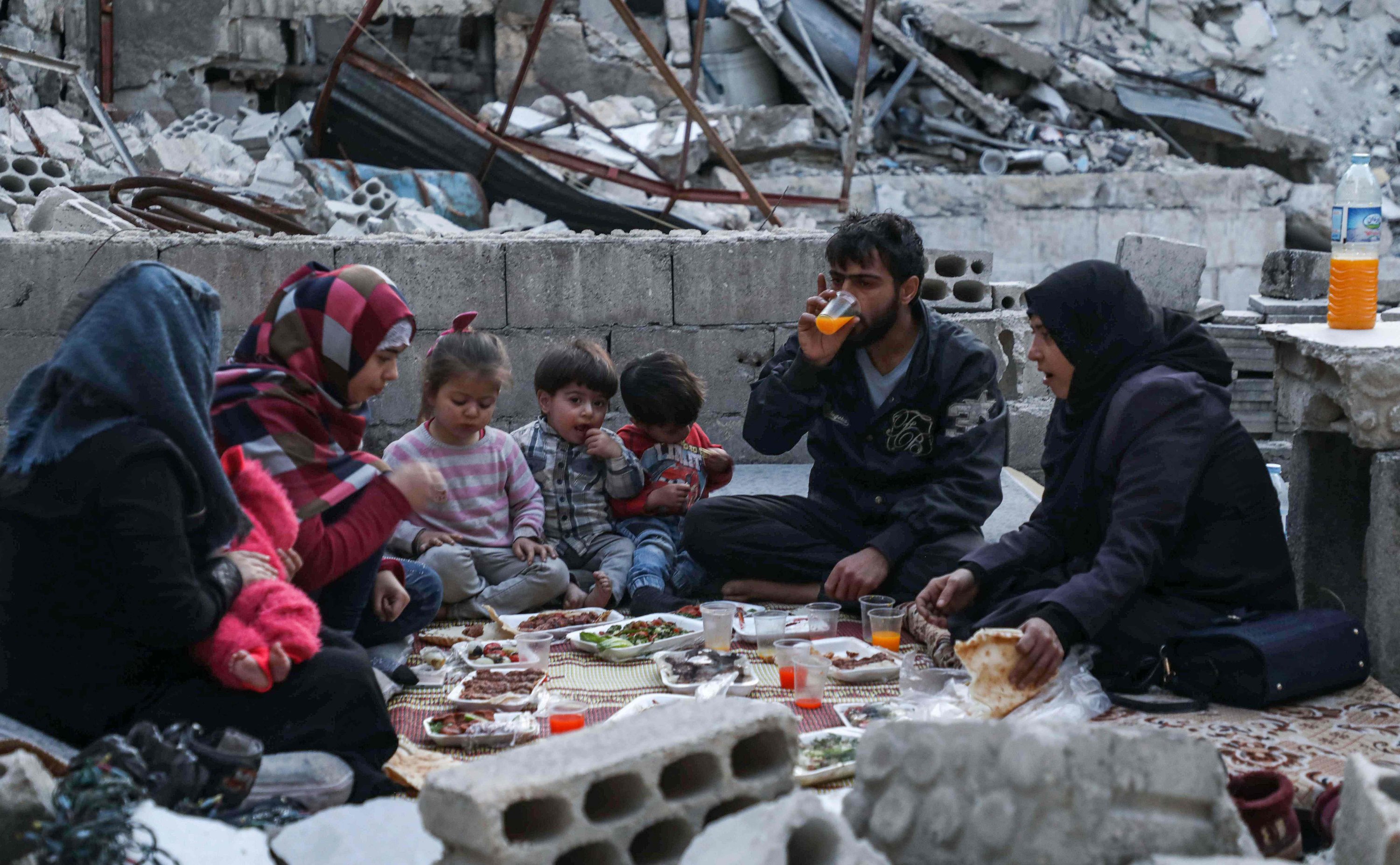 Members of the displaced Syrian family of Tariq Abu Ziad, from the town of Ariha in the southern countryside of Idlib province, break their fast together for the sunset 'iftar' meal in the midst of the rubble of their destroyed home upon their return to the town, May 4, 2020. (AFP)