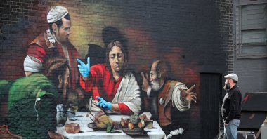 Artist Lionel Stanhope poses by his mural in Ladywell depicting the" Supper at Emmaus" by Caravaggio with added protective gloves, following the outbreak of the coronavirus, London, Britain, May 5, 2020. (Reuters Photo)