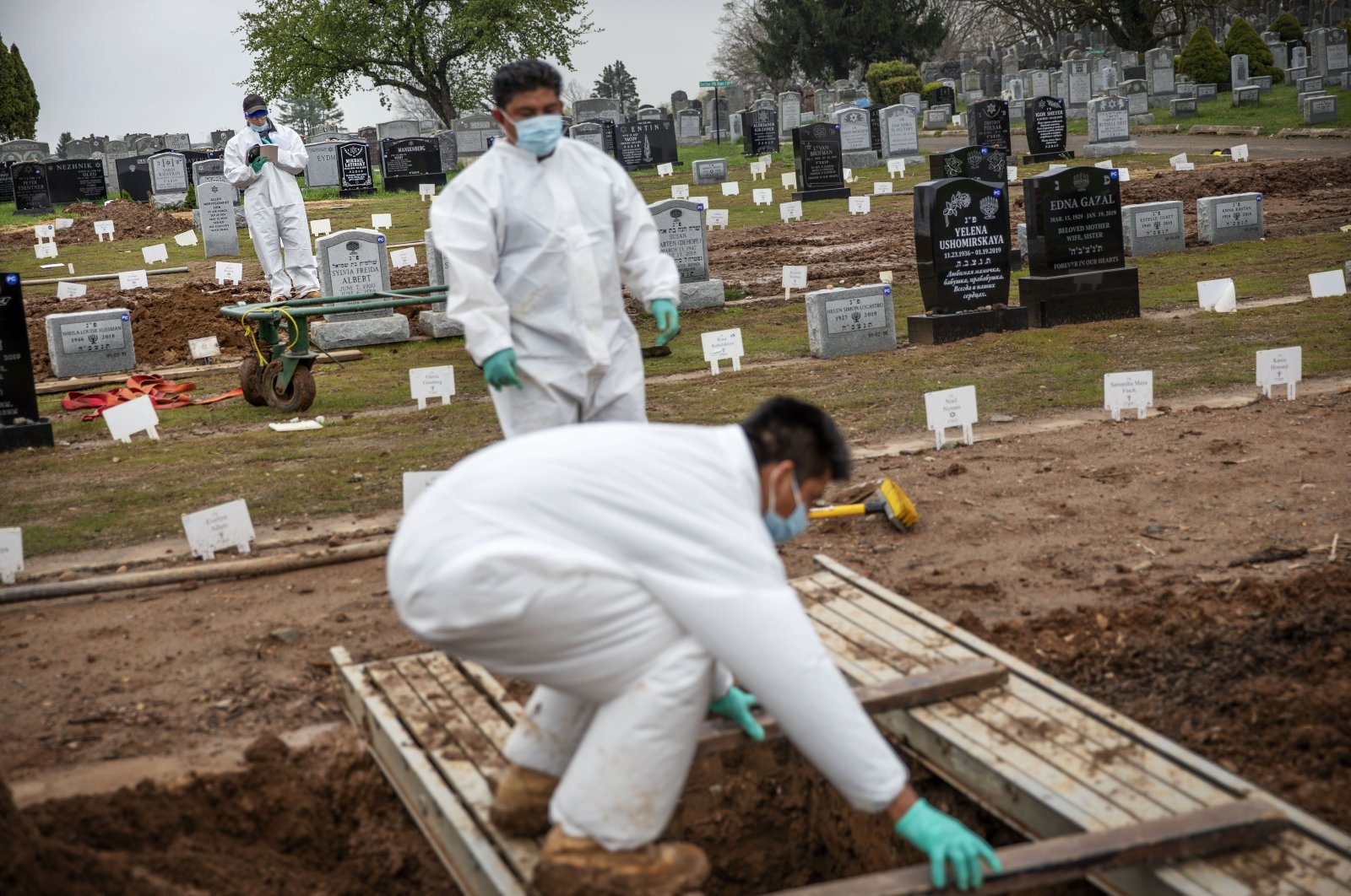 A rabbi (in the background) finishes a prayer during a burial service as gravediggers prepare a plot for the next burial at a cemetery in Staten Island, New York, April 8, 2020. (AP Photo)