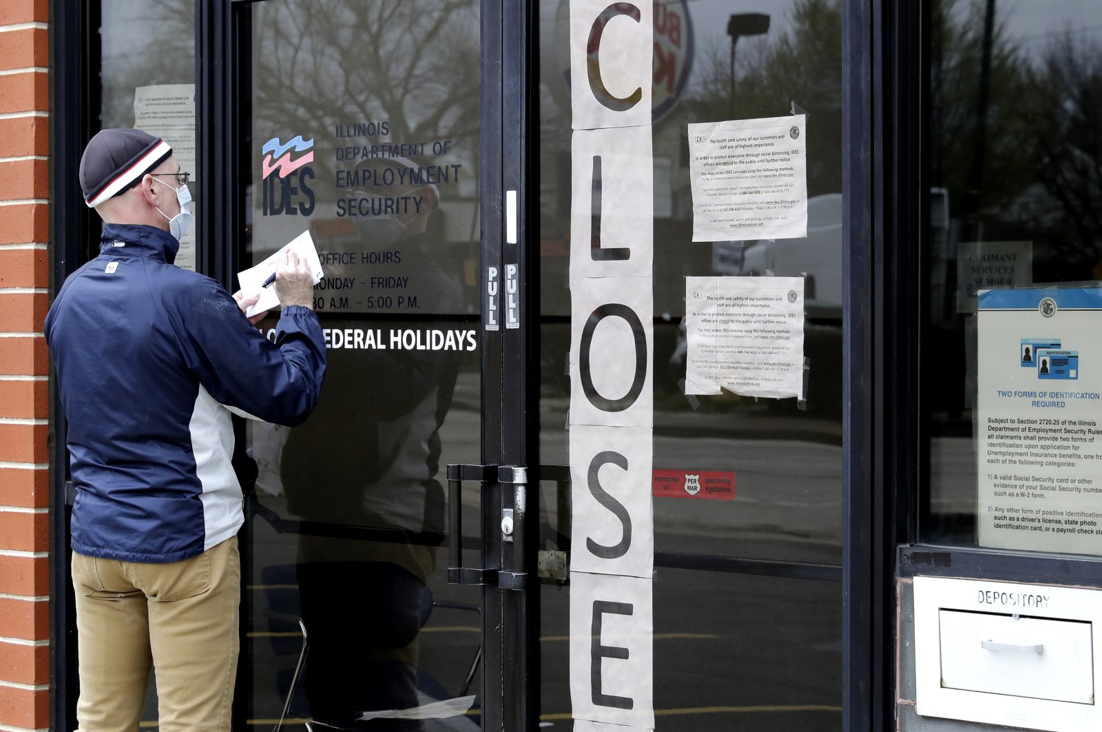 A man writes information in front of Illinois Department of Employment Security in Chicago, April 30, 2020. (AP Photo) 