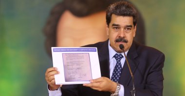 President Nicolas Maduro holds a copy of a written agreement that allegedly bears Guaido’s signature as evidence during an online press conference, Caracas, May 6, 2020. (AP Photo)