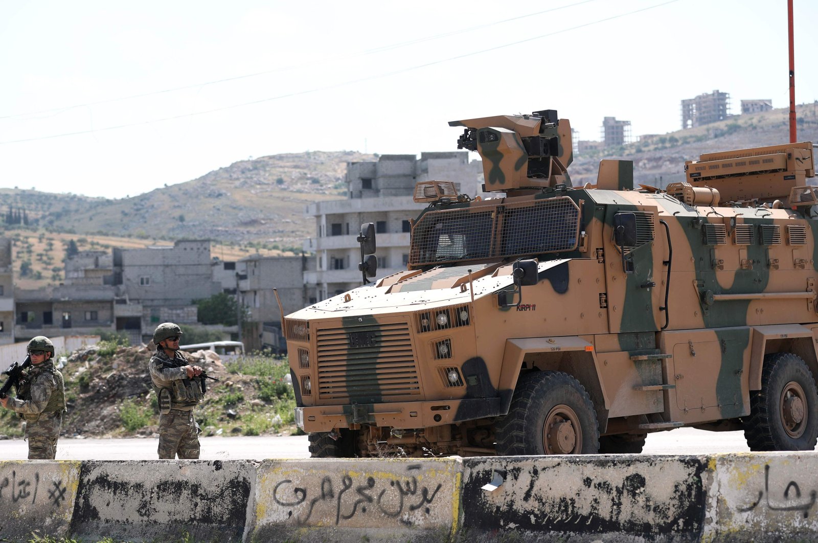 Turkish troops stand next to one of their armoured vehicles as they secure the road on the M4 highway between Saraqeb and Ariha in Syria's Idlib province, May 7, 2020. (AFP)