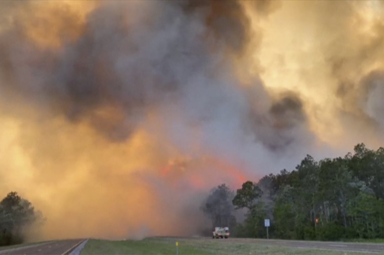 In this image made from video taken May 6, 2020 by the Florida Department of Agriculture and Consumer Services, fire and smoke rise from trees alongside a road in Santa Rosa County, Florida. (AP Photo)