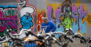A man delivering goods passes two COVID-19 related murals, one of a smurf reading "I Hate Corona," Amsterdam, the Netherlands, May 1, 2020. (AP Photo)