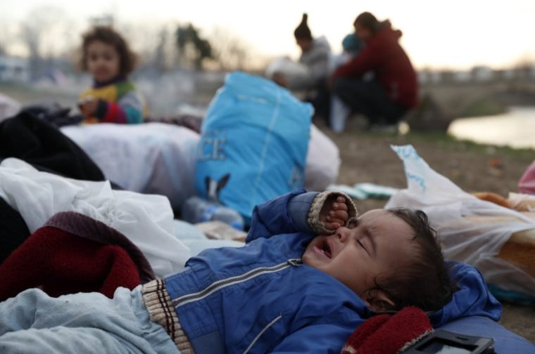 A baby cries as migrants gather next to a river in Edirne, Turkey, near the Turkish-Greek border, March 4, 2020. (AP Photo)