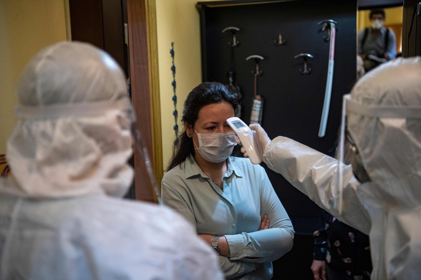 A health officer wearing protective clothing checks the temperature of a resident, believed to have been in contact with coronavirus patients, before collecting swab samples, in Istanbul on May 7, 2020. (AFP Photo)