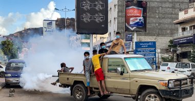 Youth wearing masks as a precaution due to COVID-19, sit in the back of a truck carrying out a fumigation in an area in Yemen's southern coastal city of Aden, May 5, 2020. (AFP Photo)