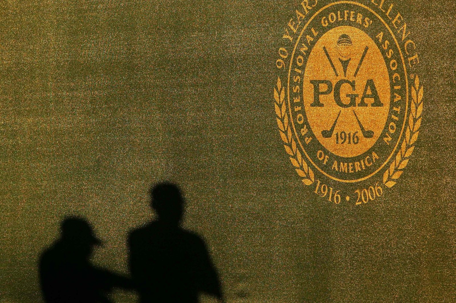 Two shadows of grounds crew are seen on the wall near the PGA logo during practice for the 2006 PGA Championship at Medinah Country Club in Medinah, U.S., Aug. 16, 2006. (AFP Photo)