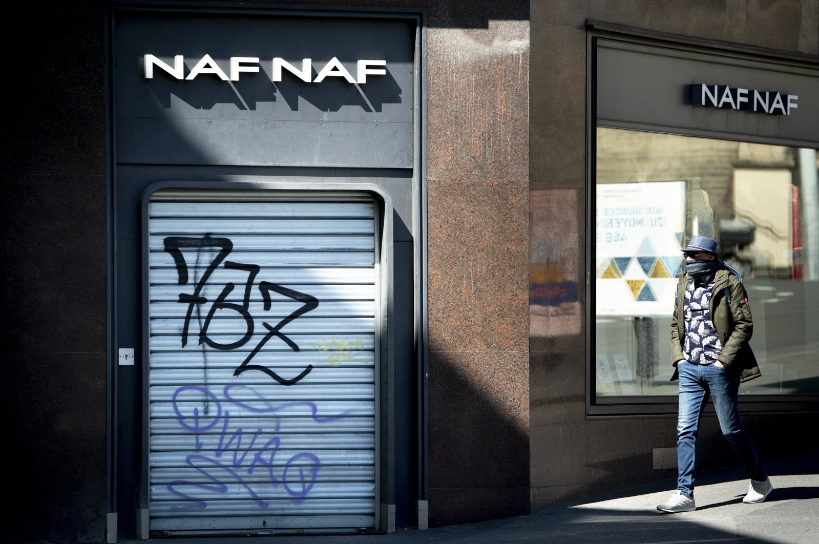 A man walks in front of a closed shop on a shopping street during the state of emergency for the COVID-19 outbreak, Lausanne, Switzerland, May 4, 2020. (AP Photo)