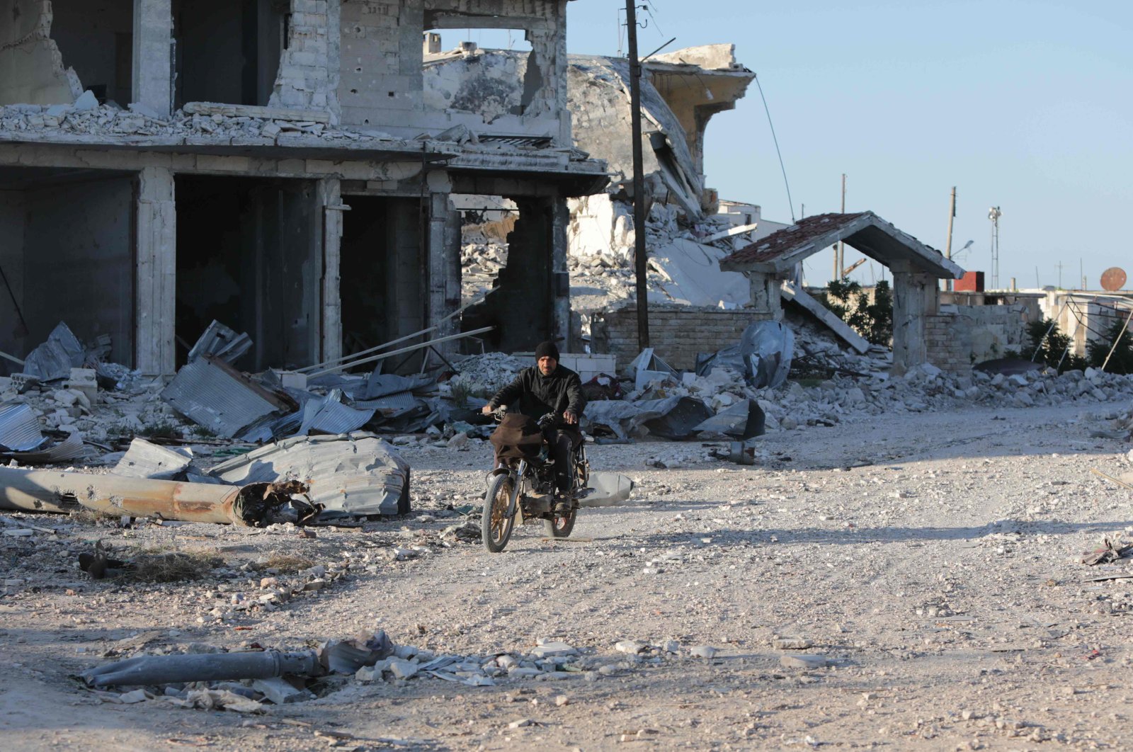 A Syrian man rides his motorcycle in al-Nayrab, a town ravaged by pro-regime forces' bombardment near the M4 strategic highway, Idlib, northwestern Syria, May 6, 2020.