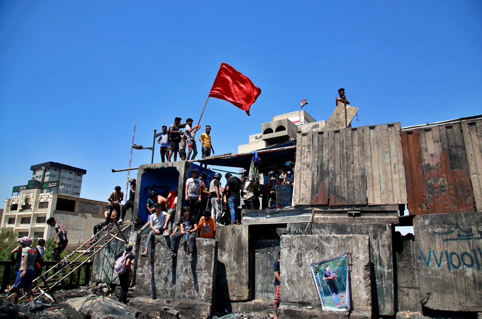 Anti-government protesters stage a sit-in on barriers set up by security forces to close the Jumhuriyah Bridge leading to the Green Zone government area, during ongoing protests in Baghdad, Iraq, May 10, 2020. (AP Photo)
