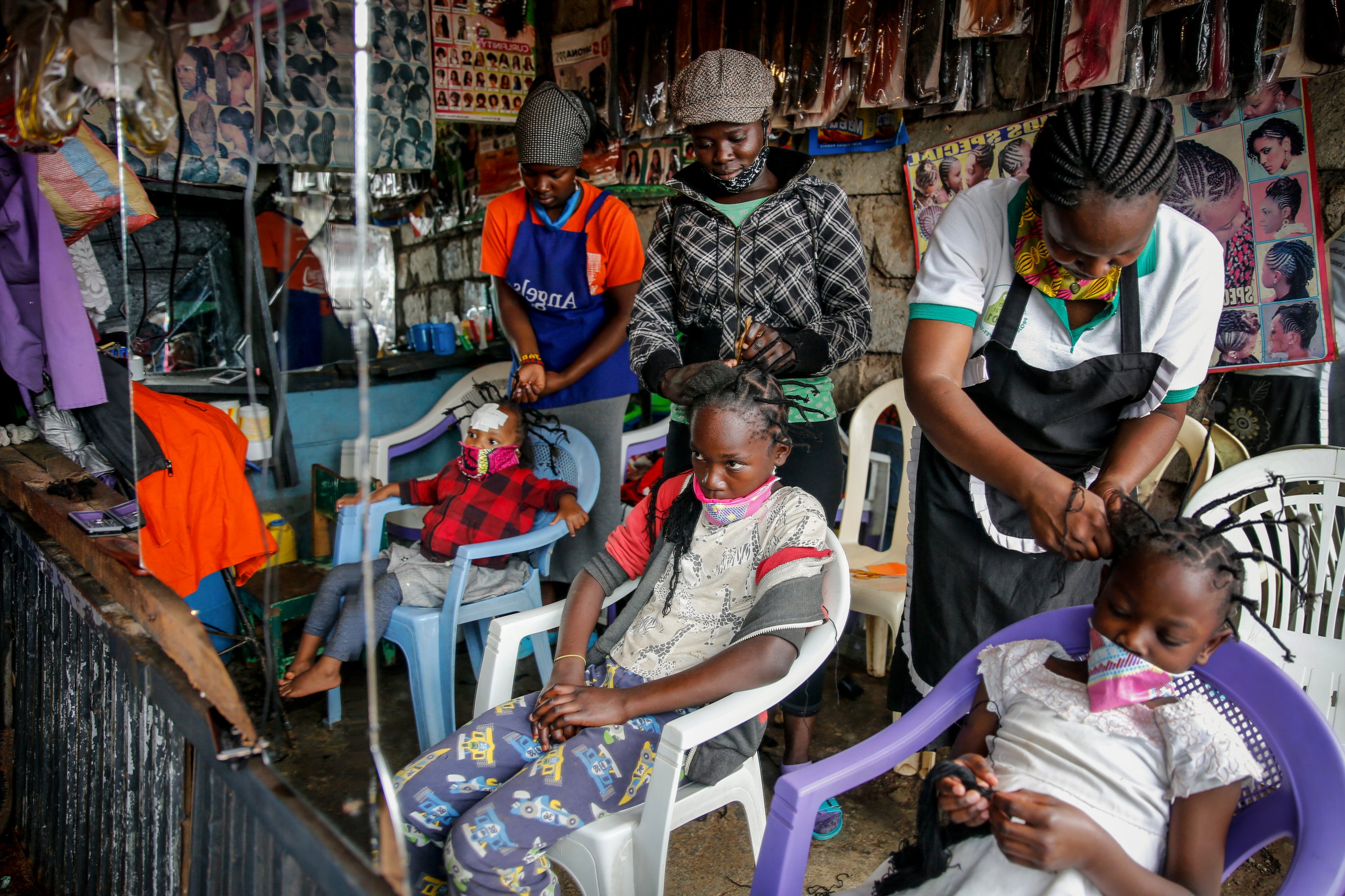 Gettrueth Ambio (C), Jane Mbone (R), and Hamida Bashir (L), have their hair styled in the shape of the coronavirus, at the Mama Brayo Beauty Salon in the Kibera slum, or informal settlement, in Nairobi, Kenya, May 3, 2020. (AP Photo)