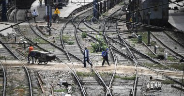Commuters walk through the tracks at the railway station in New Delhi on May 11, 2020. (AFP Photo)