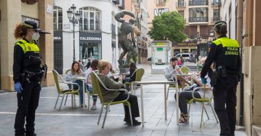 Police measure distance between tables at a bar terrace in downtown in Zaragoza, May 11, 2020. (EPA Photo)