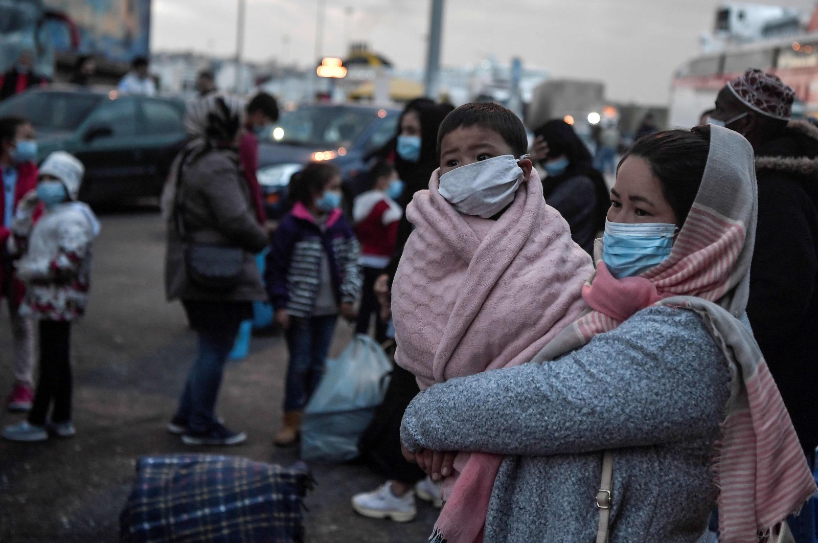 A woman holds her child as migrants transferred from the Moria camp on the island of Lesbos disembark in the port of Piraeus near Athens, May 4, 2020. (AFP Photo)