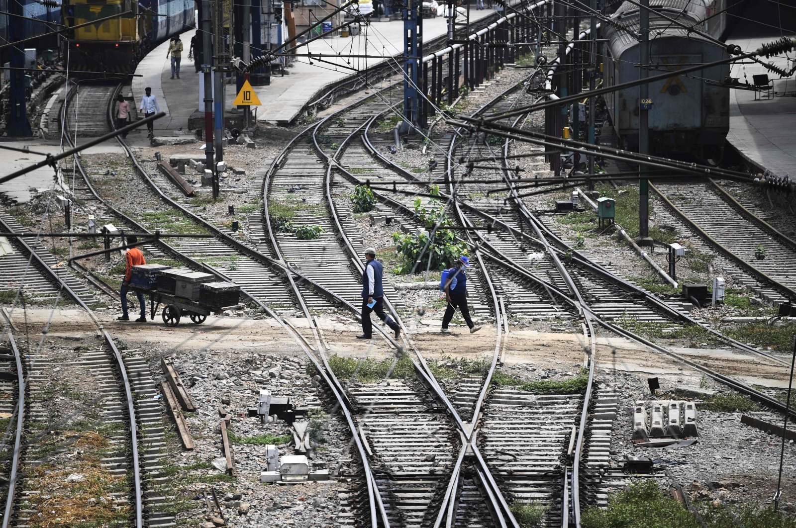Commuters walk through the tracks at the railway station in New Delhi on May 11, 2020. (AFP Photo)