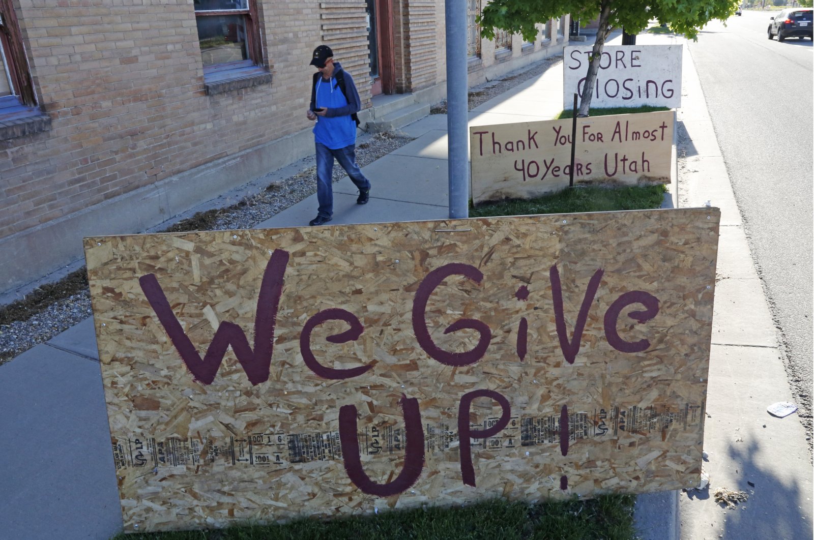 A man walks past a "We Give Up" sign outside Euro Treasures Antiques Friday, Salt Lake City, U.S., May 8, 2020. Owner Scott Evans is closing his art and antique store after 40 years. (AP Photo)