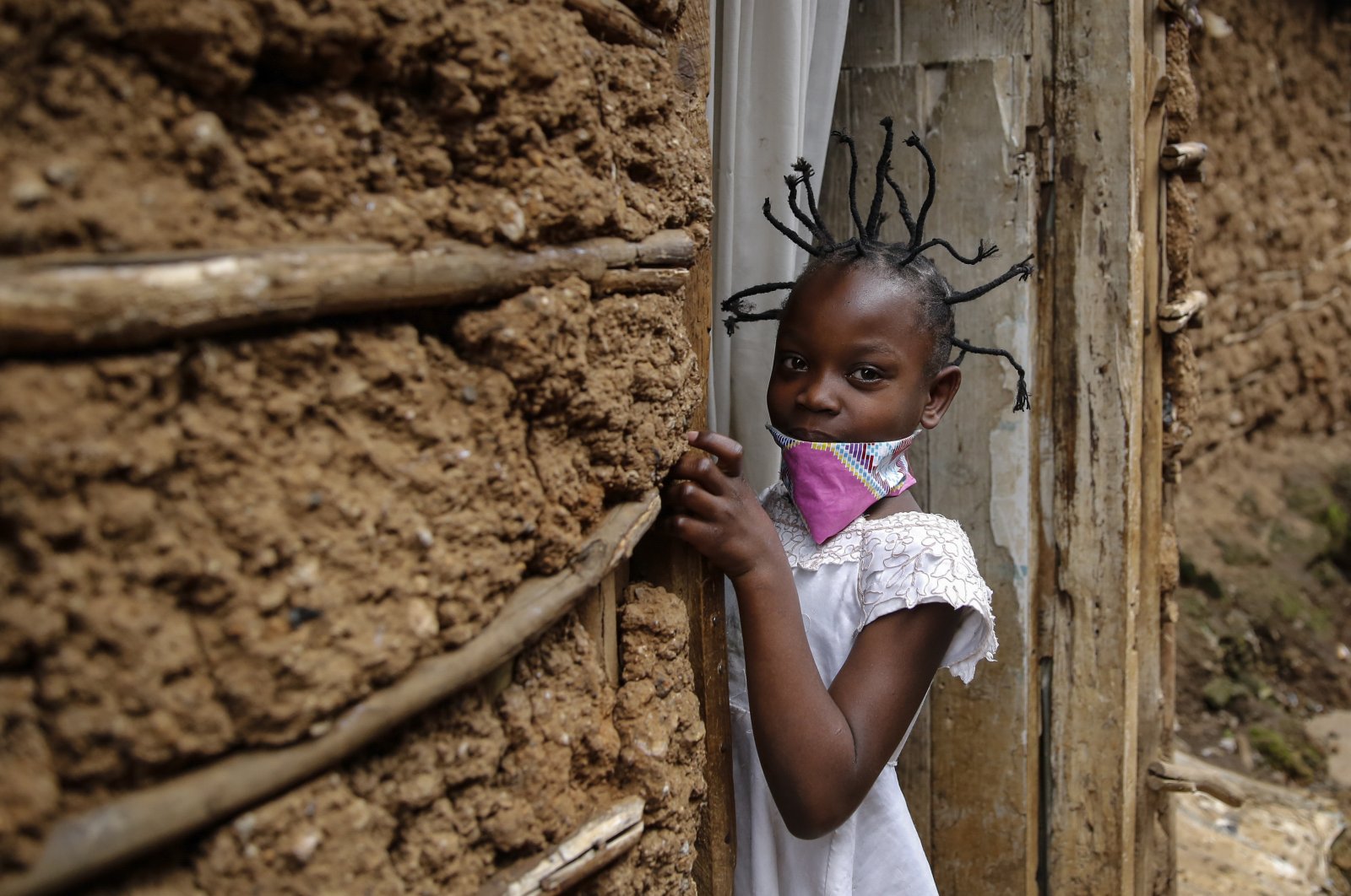 Jane Mbone, 7, arrives home after having her hair styled in the shape of the new coronavirus at the Mama Brayo Beauty Salon in the Kibera slum, or informal settlement, in Nairobi, Kenya, May 3, 2020. (AP Photo)