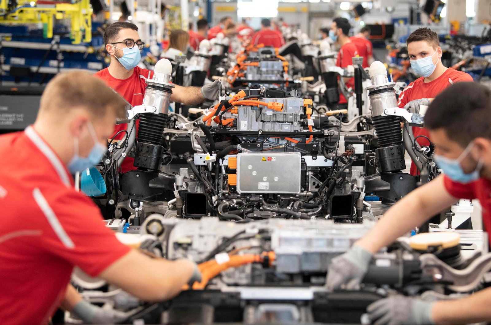 Employees of German car manufacturer Porsche wear face masks as they work on power trains for the Taycan full-electric sportscar at the production site in Stuttgart, southern Germany, on May 12, 2020. (AFP Photo)