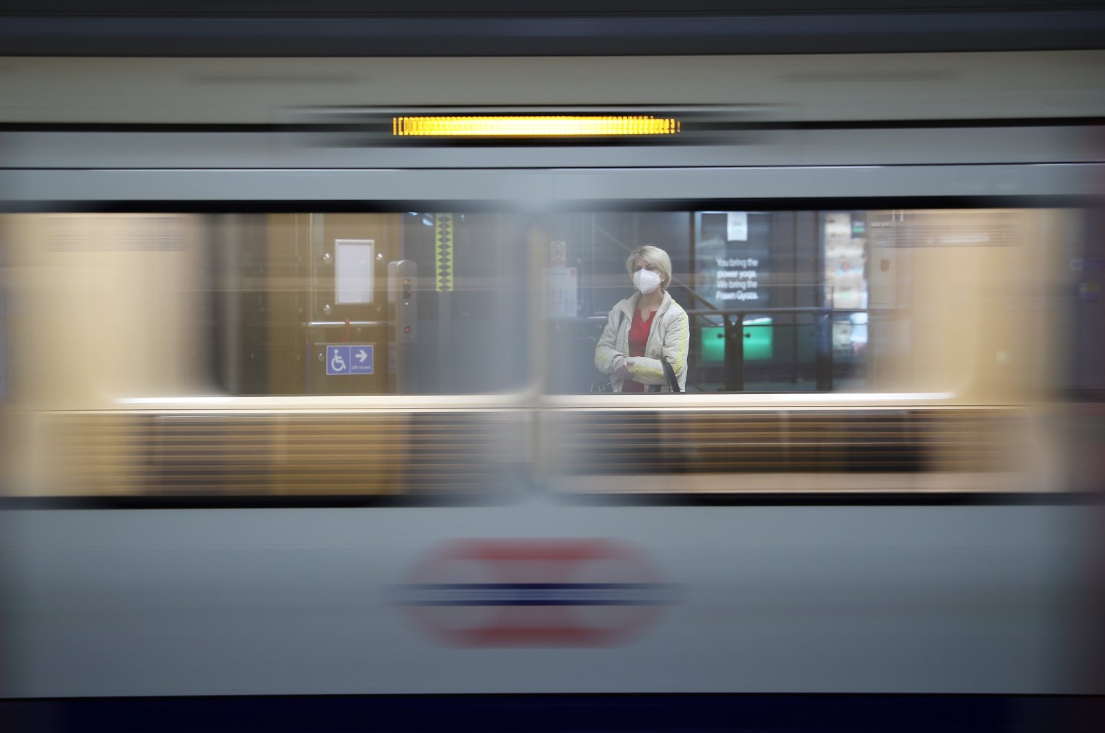 A passenger wearing a protective face mask and gloves waits for a train at Westminster Underground station, following the outbreak of the coronavirus disease London, Britain, May 12, 2020. (Reuters Photo)