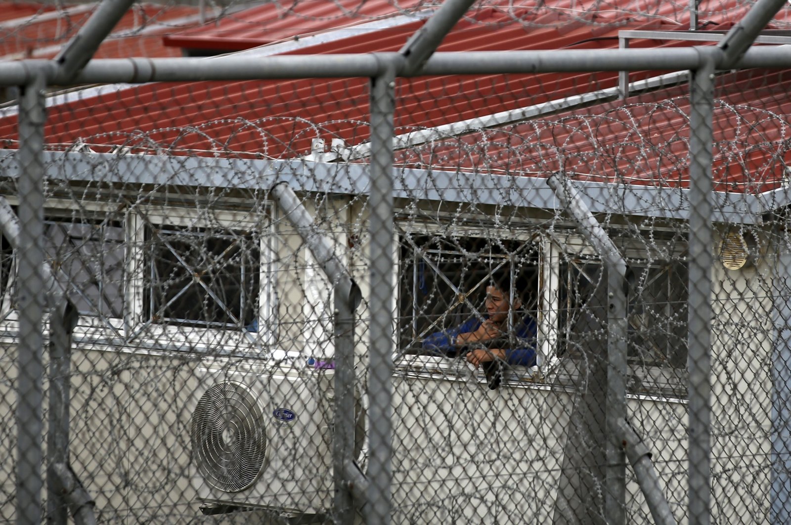 In this file photo dated Sunday, March 8, 2020, a migrant looks out from a detention center in the village of Fylakio, Evros region, near the Greek-Turkish border. (AP Photo)