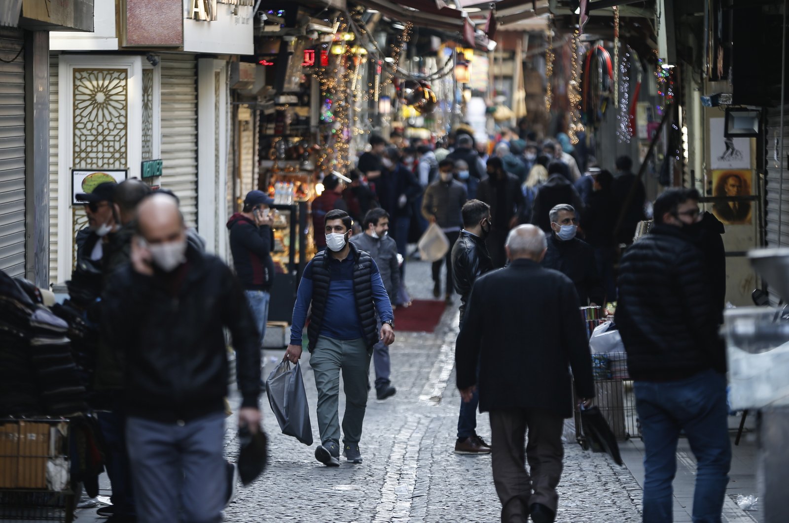 People, some wearing masks as a preventive measure against the spread of coronavirus, walk at Eminonu Bazaar in Istanbul, Friday, April 17, 2020, just hours before the start of a two-day curfew declared by Turkey's government in an attempt to control the spread of coronavirus. (AP Photo)
