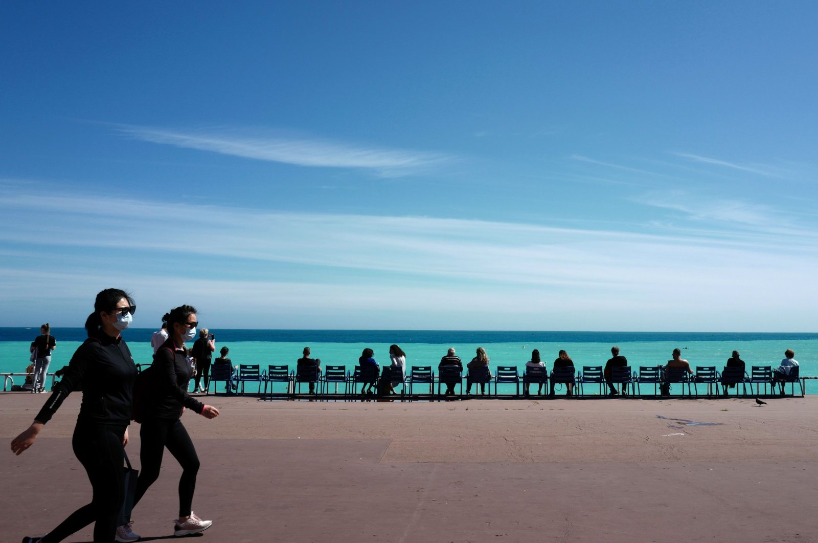 People wearing protective facemasks walk on the "Promenade des Anglais", in the French Riviera city of Nice, southern France, on May 12, 2020 on second days after France eased lockdown measures taken to curb the spread of the COVID-19. (AFP Photo)