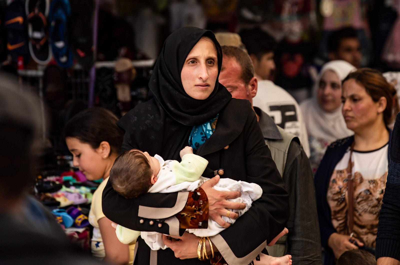 A woman walks with a baby at the main market of the city of Qamishli in Syria's northeastern Hasakah province, May 12, 2020. (AFP Photo)