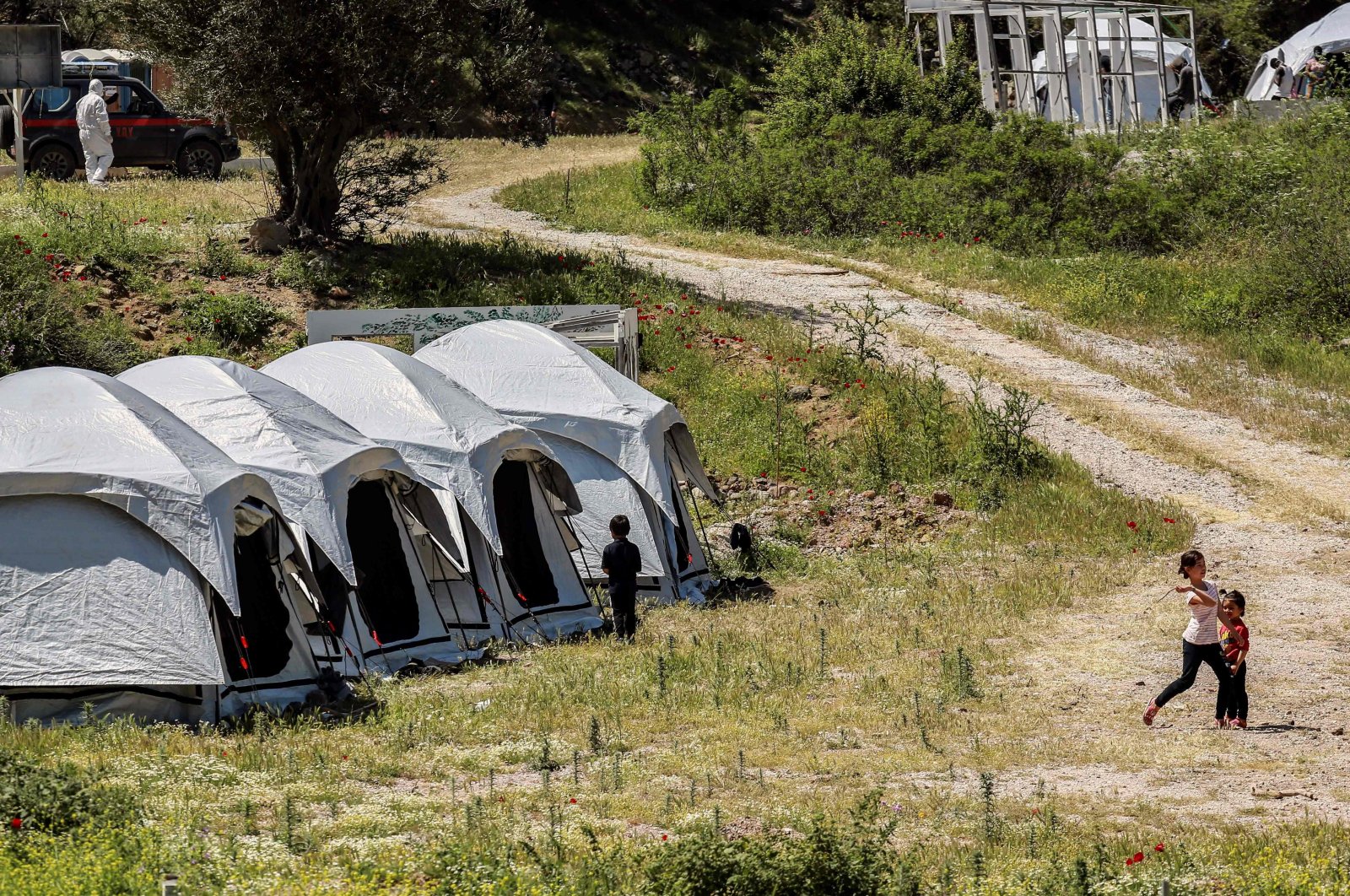 Children play outside the tents at a migrant and refugee camp where cases of COVID-19 were detected, on the Greek island of Lesbos, on May 13, 2020, as the country faces the novel coronavirus pandemic. (AFP Photo)