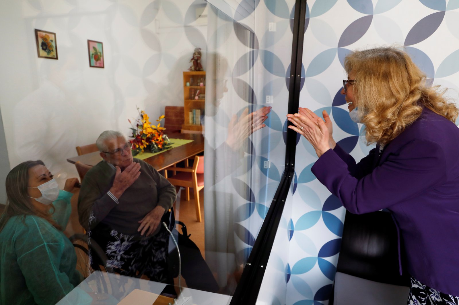 Maria das Merces speaks with her father Adriano Borges through a glass window to prevent infection at an elderly residence as the spread of the coronavirus disease continues, Montijo, Portugal, May 12, 2020.