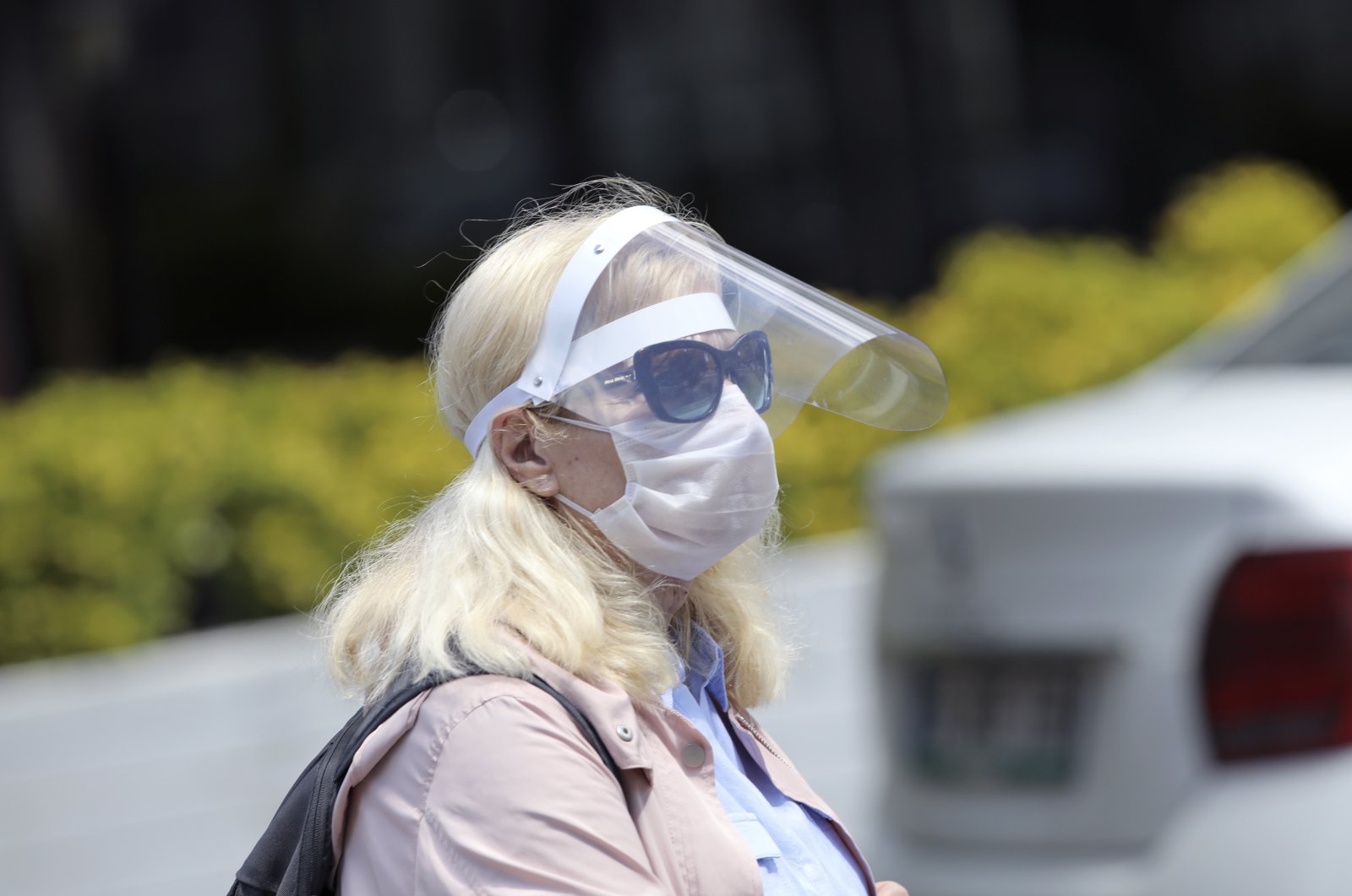 A woman wearing a face shield and mask walks in a local park in Ankara, Turkey, May 10, 2020. (AP Photo)