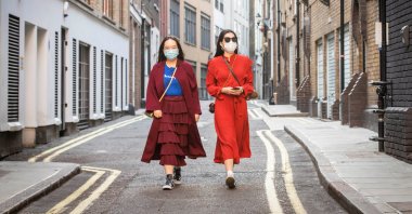 Two Chinese girls wearing masks walk down an empty street in Soho, London, Thursday, May 7, 2020. (PA via Reuters)
