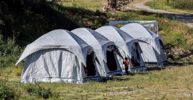 Children play outside the tents at a migrant and refugee camp where cases affected by the COVID-19 were detected, on the Greek mediterranean island of Lesbos, May 13, 2020. (AFP)