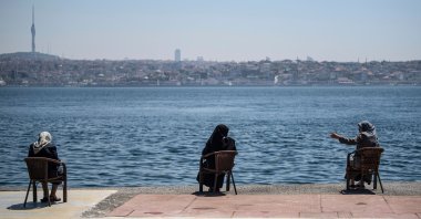 Women wearing protective face masks sit apart following social distancing measures at the seaside overlooking the Bosporus in Istanbul, Turkey, May 10, 2020. (AP Photo)