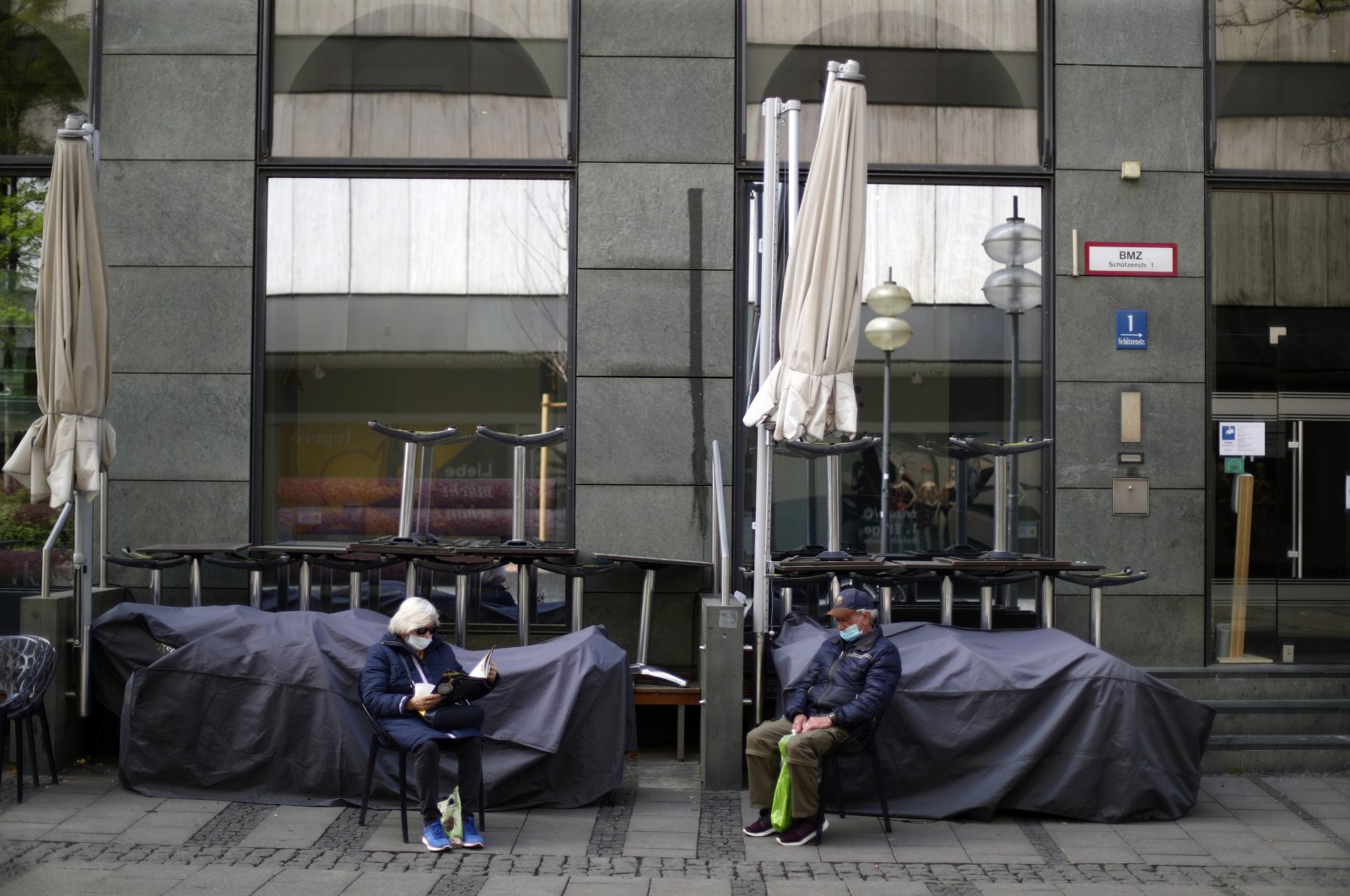 An elderly couple sits outside a closed bar during the lockdown due to the coronavirus outbreak downtown in Munich, Germany, May 9, 2020. (AP Photo)