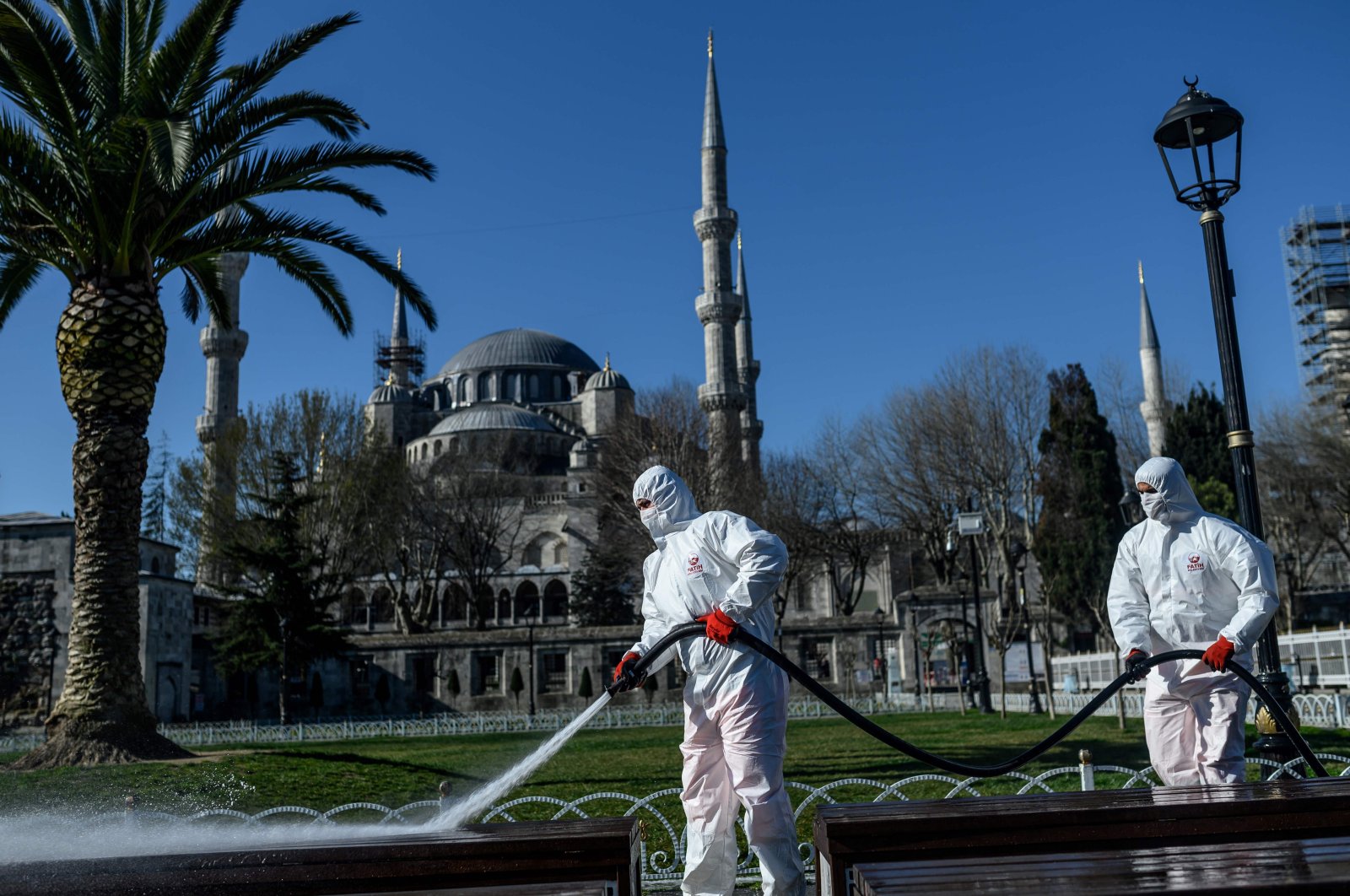 Members of the Fatih Municipality disinfect Istanbul's Sultanahmet Square with the Blue Mosque in the background to prevent the spread of the coronavirus, March 21, 2020. (AFP Photo)