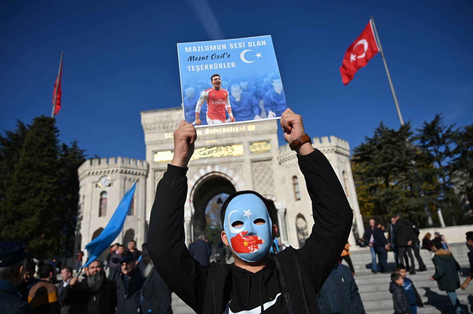 In this file photo taken on December 14, 2019 a supporter of China's Muslim Uighur minority holds a placard of Arsenal's Turkish origin German midfielder Mesut Ozil reading "Thanks for being our voice" during a demonstration at Beyazid square in Istanbul. (AFP Photo)