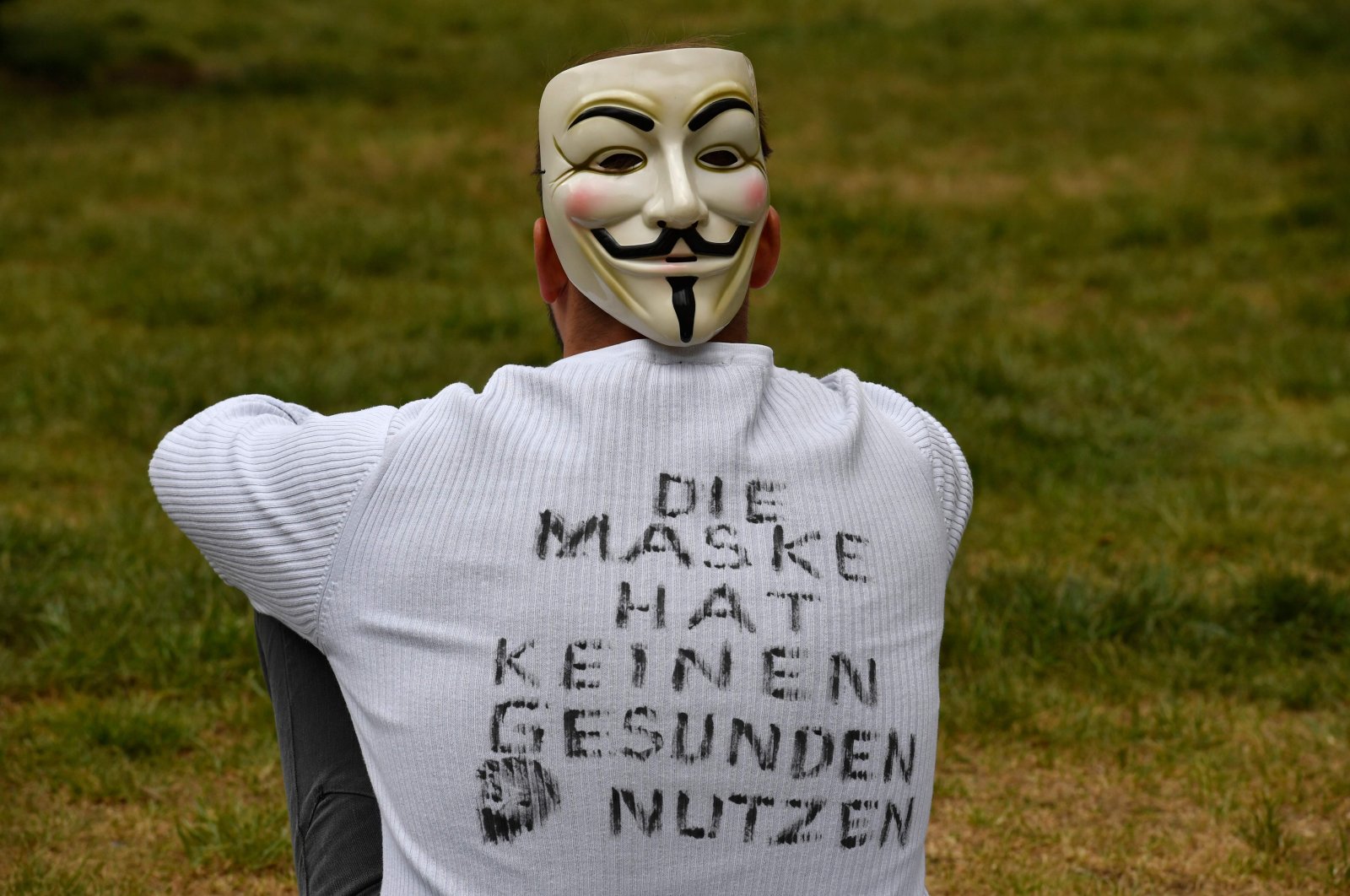 A demonstrator wearing a mask and a T-shirt with inscriptions reading 'The mask has no healthy use' sits in the demo area during a protest against the coronavirus-related restrictions in Berlin, May 2, 2020. (AFP Photo)