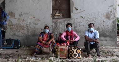 Migrant workers and families wait for transport to go to their hometowns in Uttar Pradesh and Bihar states after police stopped them from crossing the Delhi-Uttar Pradesh states border on foot as the government eased a nationwide lockdown as a preventive measure against the COVID-19 coronavirus, New Delhi, May 15, 2020. (AFP Photo)
