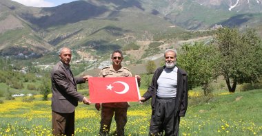 Locals walk in a plateau cleared of the PKK terrorist elements with a Turkish flag at hand, Hakkari, May 17, 2020. (AA)