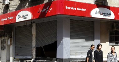 People walk past the looted premises of cellphone company Syriatel, which is owned by Rami Makhlouf, the cousin of Syrian dictator Bashar Assad, in Daraa, Syria, March 21, 2011. (Reuters Photo)